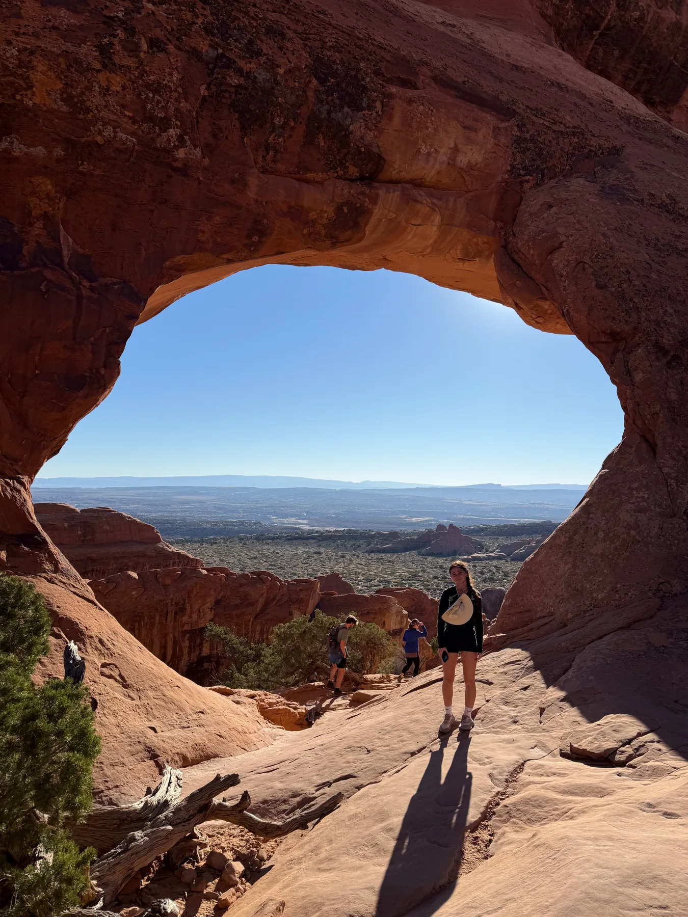 Lyla standing beneath a sandstone arch with the landscape beyond