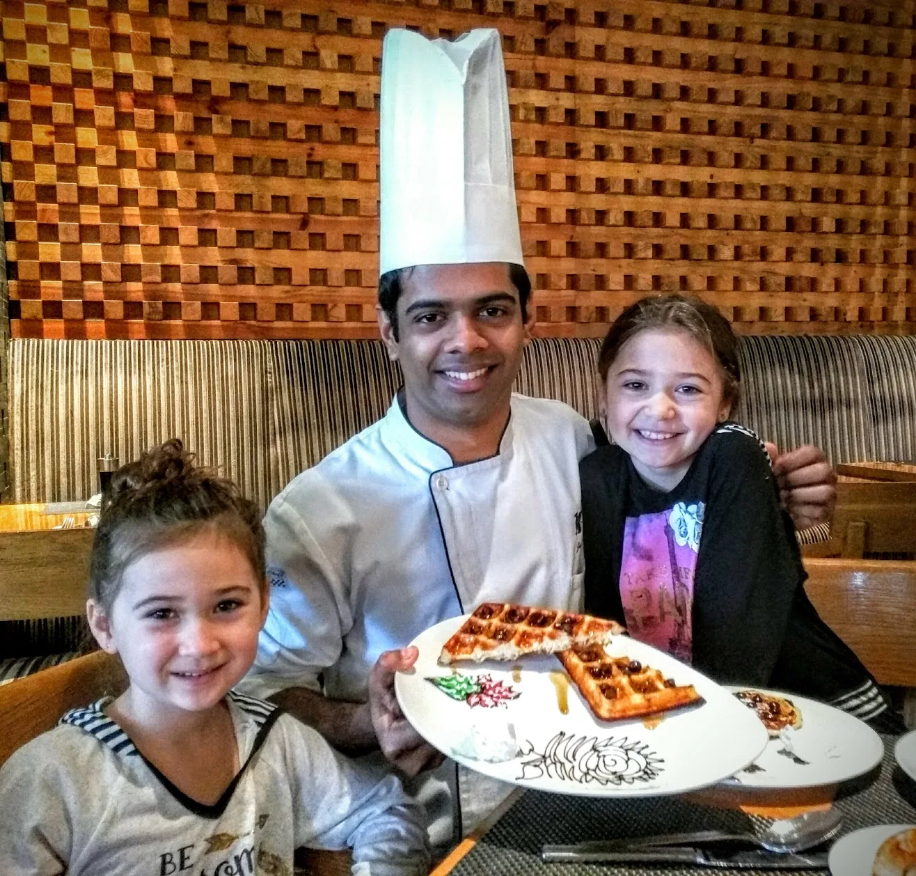Two sisters with a chef and a plate of waffles