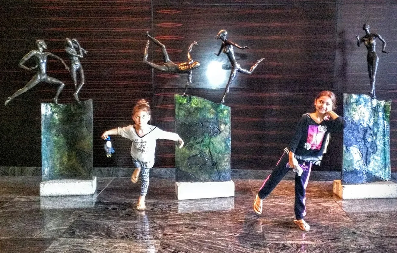 Two sisters copying the poses of dancing sculptures