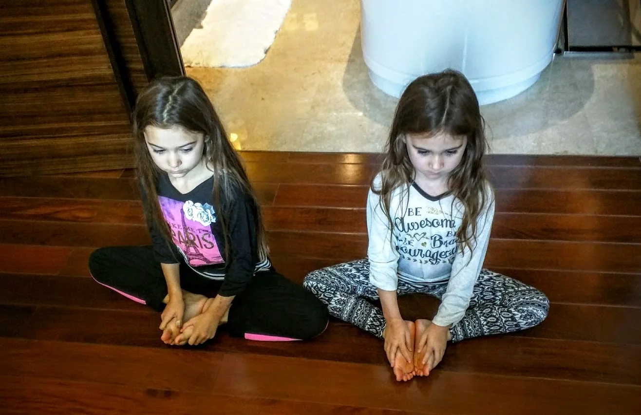 Two sisters sitting on the floor practicing yoga