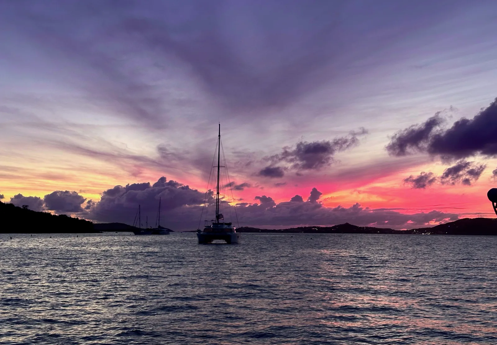 A sailboat at anchor beneath a colorful sunset at Salomon Bay